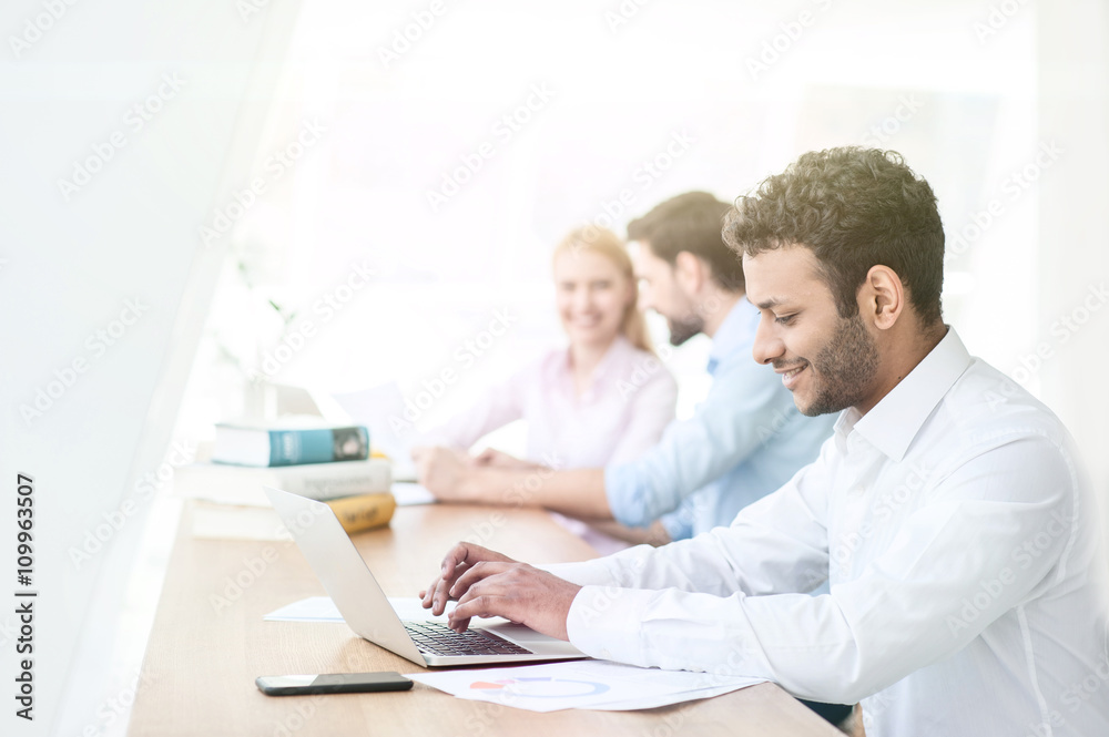 Cheerful male student is working on computer Cheerful male student is working on computer