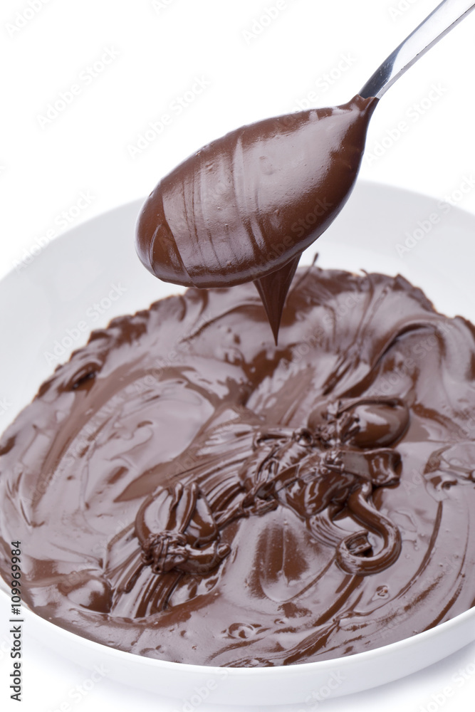Fototapeta premium spoon full of melted chocolate over a bowl of melted chocolate