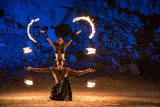 Fireshow performance in the desert near the rock illuminated with blue. Motions are blurred