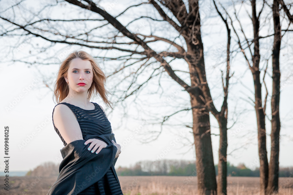 Beautiful girl in black dress witg folded arms outdoors. Sad and lonely woman in the field. Beautiful girl in black dress witg folded arms outdoors. Sad and lonely woman in the field.