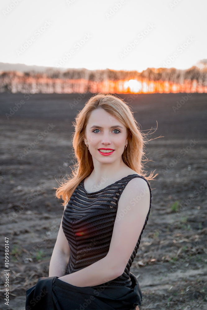 Portrait of a beautiful blonde girl in black dress outdoors. smiling woman. Sunset. Portrait of a beautiful blonde girl in black dress outdoors. smiling woman. Sunset.