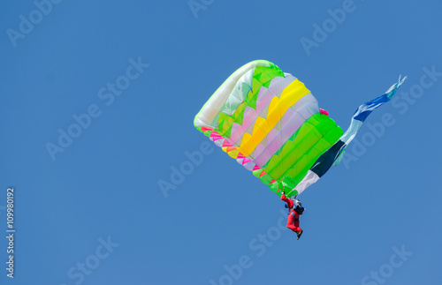 Parachutist on blue sky background with colored parachute