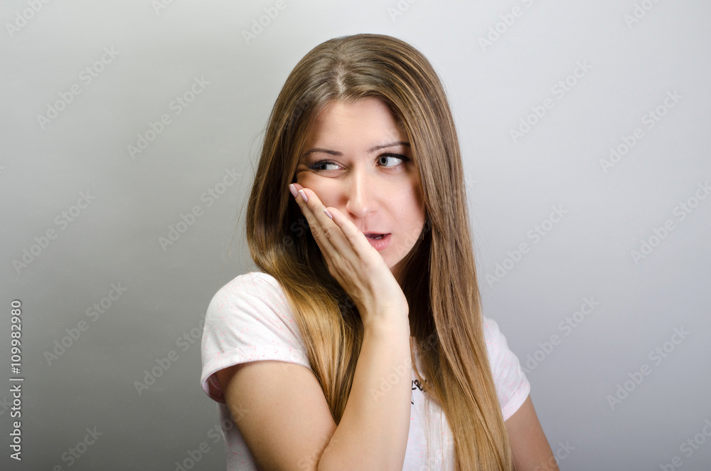 Suffering from toothache. Beautiful young woman suffering from toothache while standing against grey background Suffering from toothache. Beautiful young woman suffering from toothache while standing against grey background