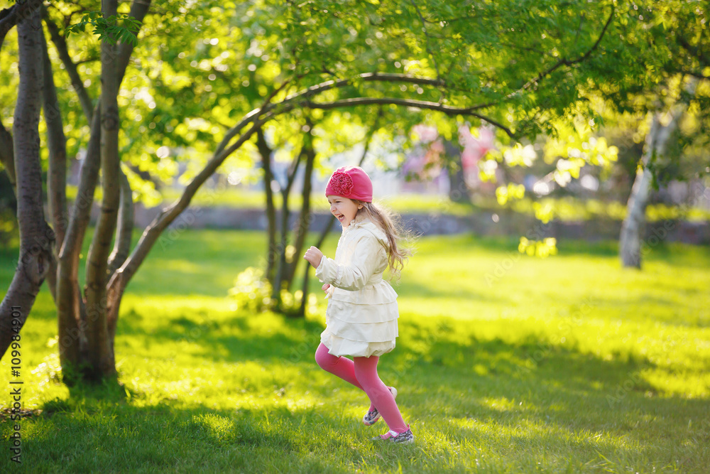 little girl running on green grass in the Park. child plays outdoor little girl running on green grass in the Park. child plays outdoor
