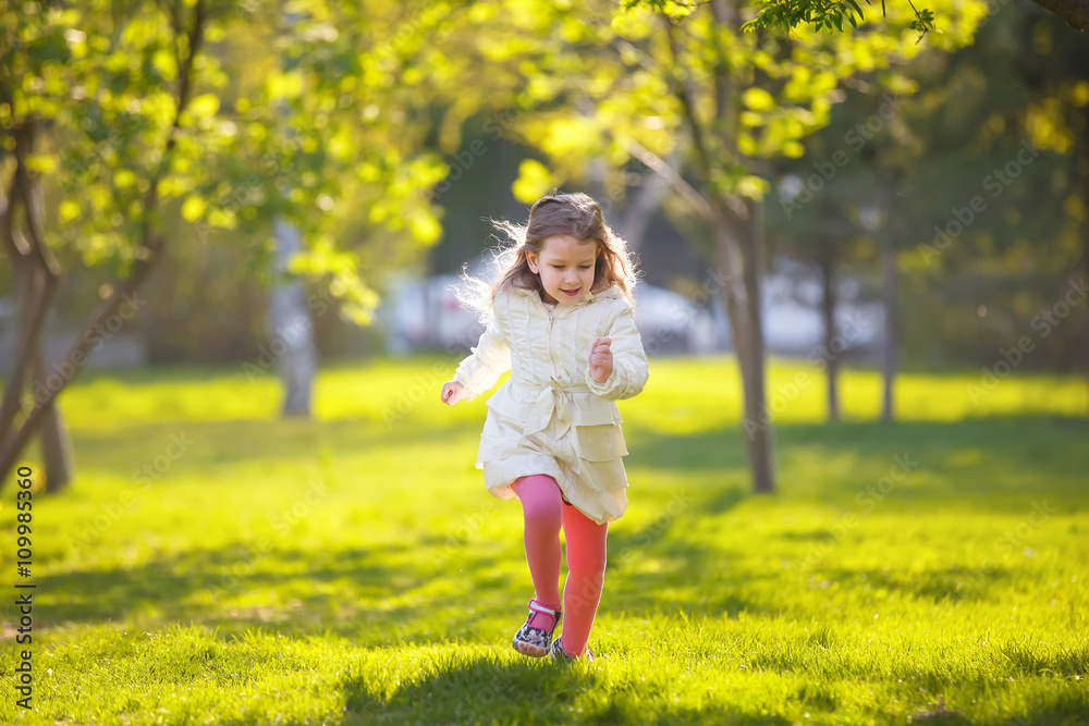 little girl running on green grass in the Park. child plays outdoor little girl running on green grass in the Park. child plays outdoor