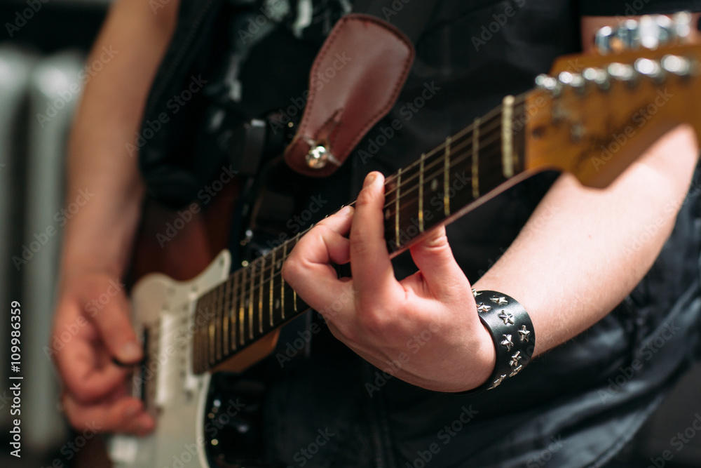 Musician playing six string electric guitar in sound recording studio. Rocker playing on electric guitar, closeup. Musical instrument closeup.