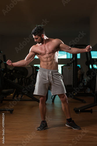 Fototapeta Naklejka Na Ścianę i Meble -  Biceps Pose Of A Young Man In Gym