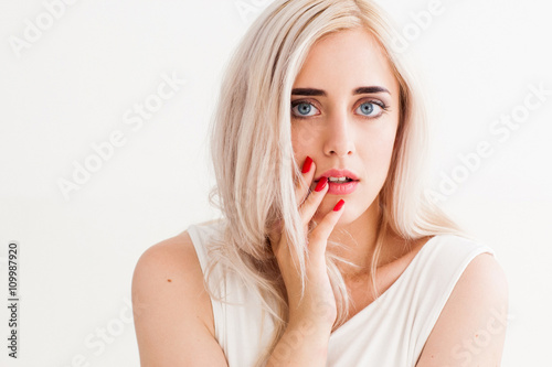 Surprised shoked girl covers her mouth and her eyes wide open. Fashion girl shows wow on a white background. Beautiful woman amazed.