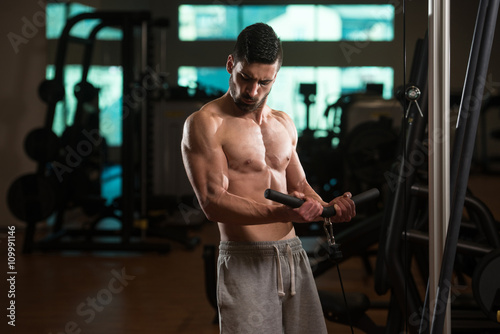 Young Man Exercising Biceps In The Gym
