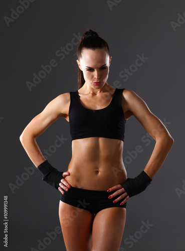 Muscular young woman  standing on gray background © lenets_tan
