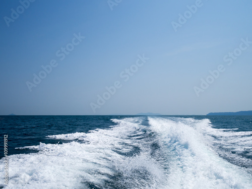 Restless foamy blue sea wake water on the sea water surface with clear blue sky while travel by speed boat in the ocean. © ieang