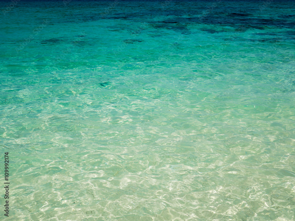 Background of transparent crystal blue sea water surface in summer.