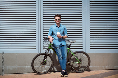 Pleasant guy standing with his bicycle 