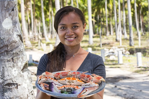 woman of Asian appearance with dishes cooked crabs