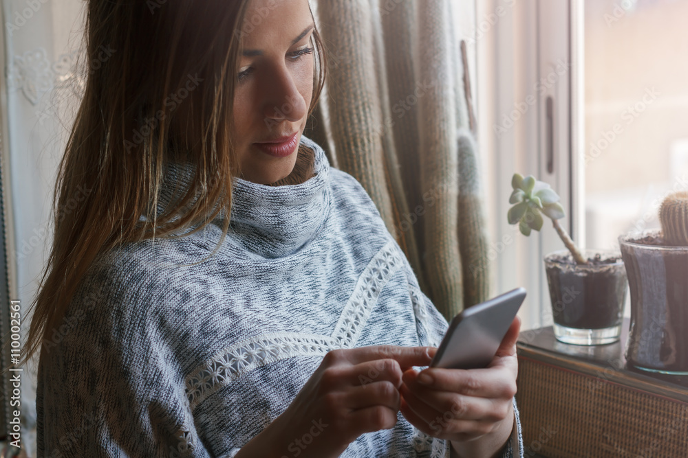 Woman using the phone with headphones at home Woman using the phone with headphones at home