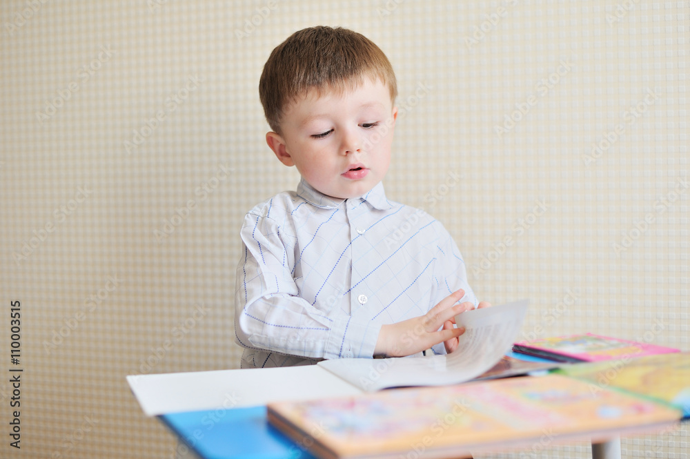 Portrait of cute boy with pen and paper at desk in classroom Portrait of cute boy with pen and paper at desk in classroom