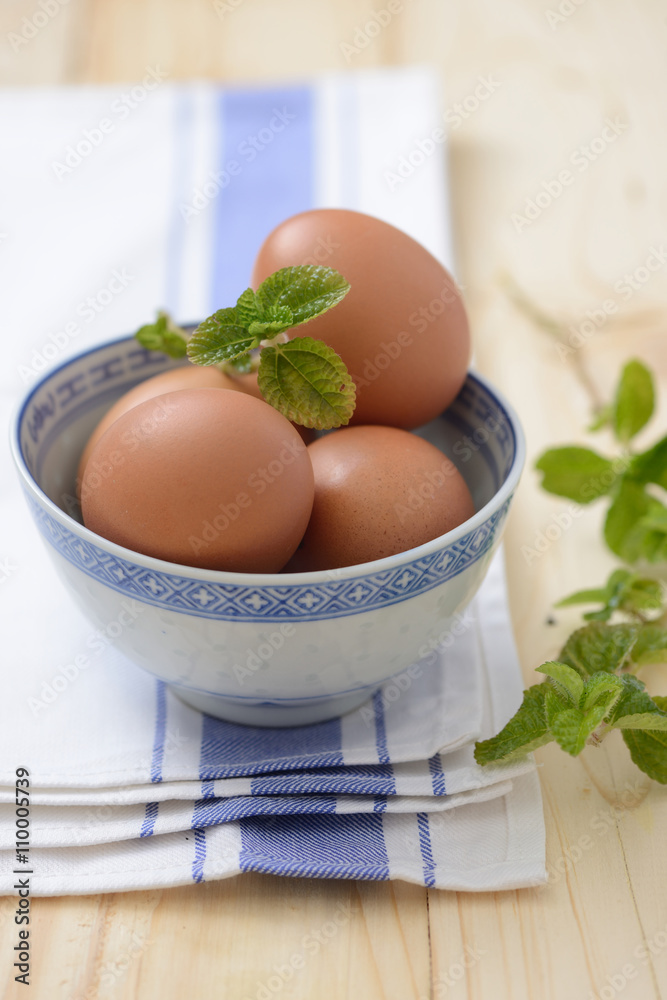 brown eggs in a bowl with mint leaf on a napkin closeup brown eggs in a bowl with mint leaf on a napkin closeup