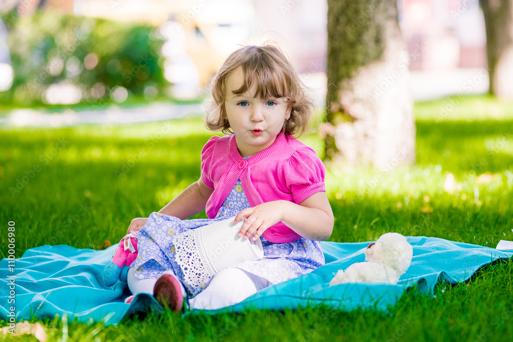 Little girl sitting in the park and reading a book