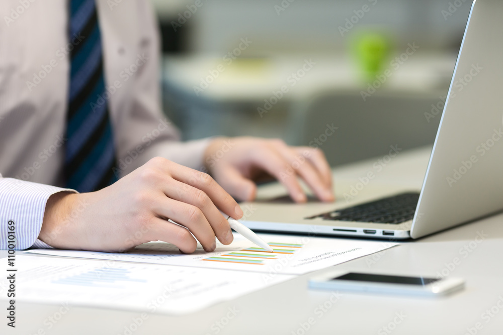 Businessman working on Laptop and printed Charts Businessman working on Laptop and printed Charts