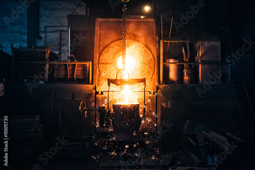Smelting metal in a metallurgical plant. Liquid iron from metal ladle pouring in castings at factory photo