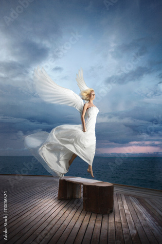 Ethereal, divine, unreal bride lfly like a bird from ocean pier. photo