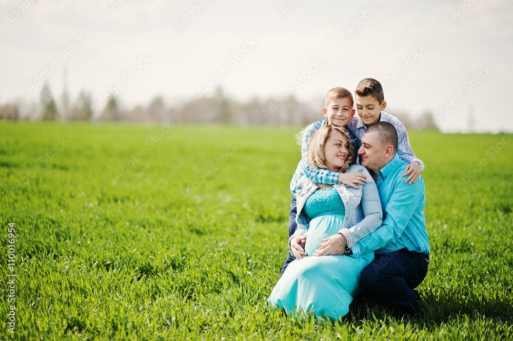 Happy pregnant family with two sons, dressed in a turquoise clot