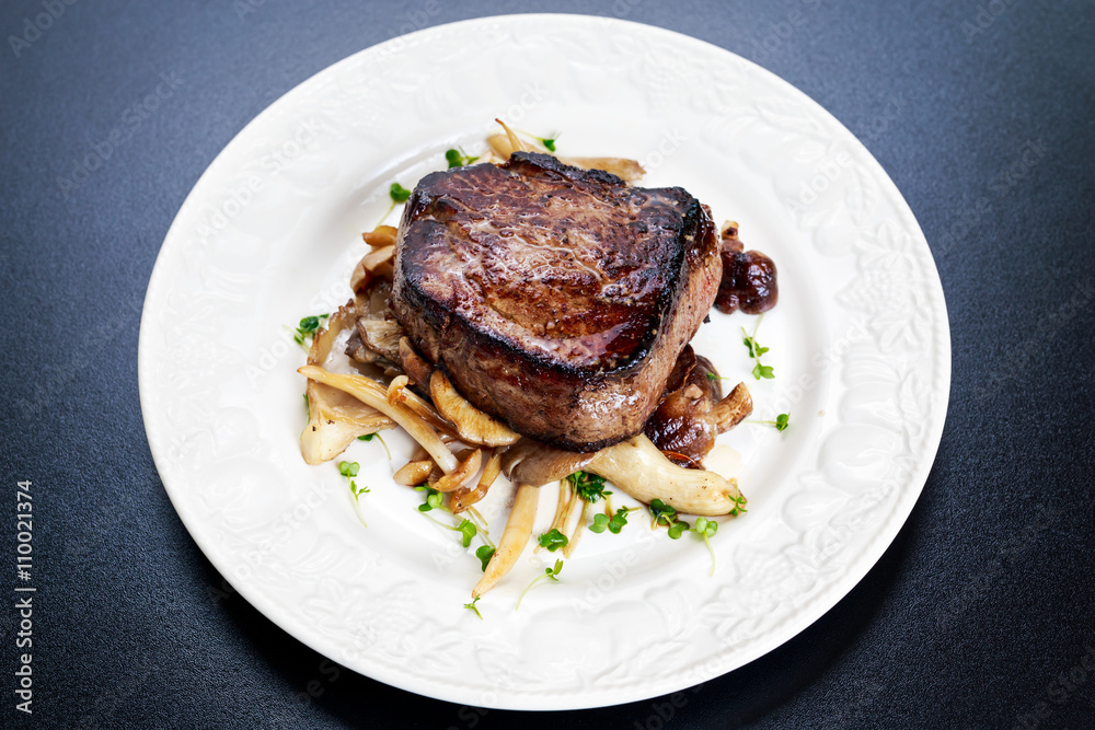 Tasty Beef Mignon steak with mushrooms and herbs on plate
