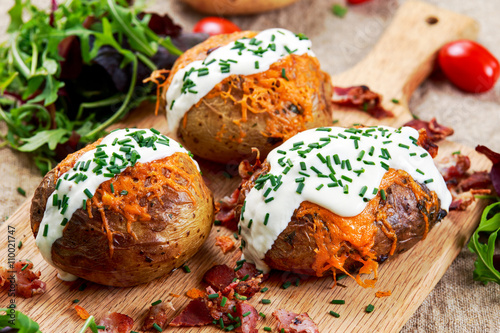 Foto Hot Baked Potato with cheese, bacon, chives and sour cream.