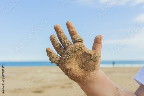 Close up hand with wet sand of a 5 year old kid