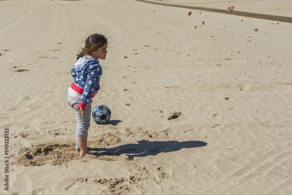 Girl throwing a ball of wet sand in the beach in a windy day in Girl throwing a ball of wet sand in the beach in a windy day in