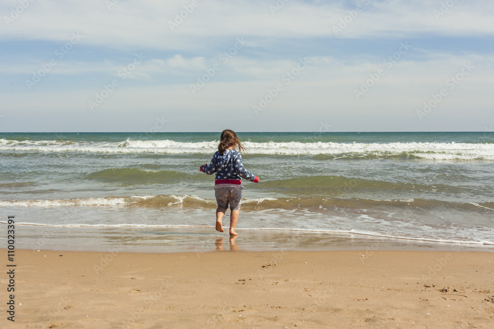 Rear view full shot girl walking to the shore of the beach in a