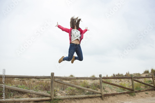 Full shot happy teenager jumping with outstretched hands near th