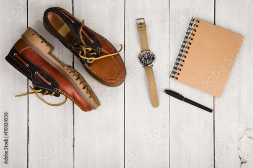 Travel concept - shoes, notepad and watch on the wooden desk