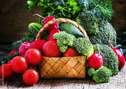 Fresh vegetables in a wicker basket: tomatoes, broccoli, cucumbe photo