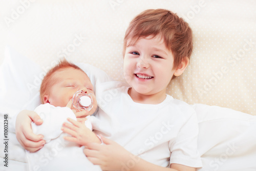 portrait of cute happy siblings. young boy holding his infant brother