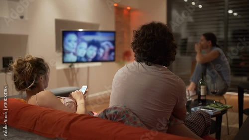 Friends sitting in the flat at night and watching television, steadycam shot
