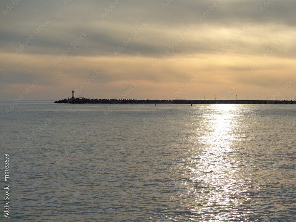 Lighthouse and path of sunlight in the sea at sunset