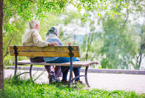 Elderly couple resting on a bench in the park