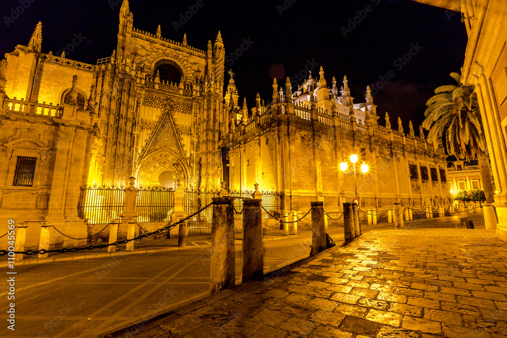 Side view of Cathedral of Seville illuminated  by night, the world's largest Gothic Cathedral and the third religious building to size, Andalucia, Spain.