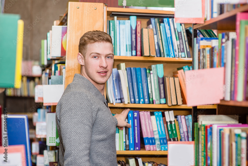 Male student chooses a book in the library Male student chooses a book in the library