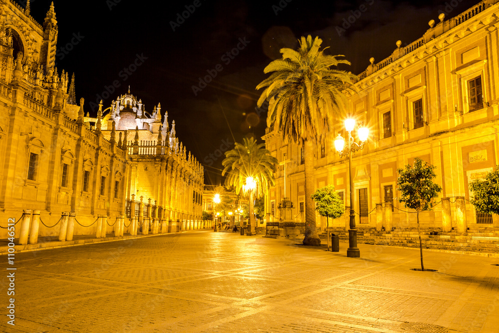 The Cathedral of Seville illuminated by night, with street and historic buildings around, the world's largest Gothic Cathedral and the third religious building to size, Andalucia, Spain.