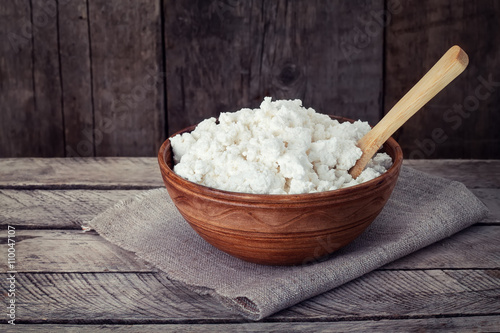 cottage cheese in clay bowl on old wooden background