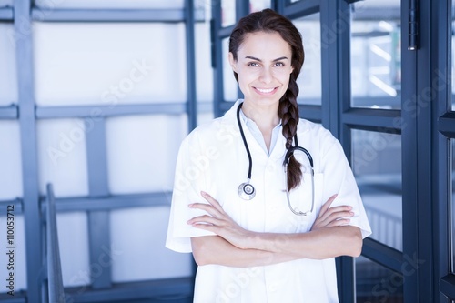 Happy female doctor standing with arms crossed