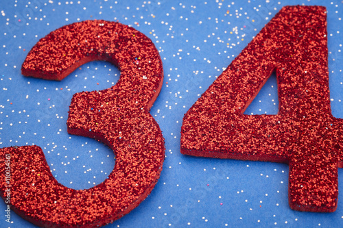 Number thirtyfour red color over a blue background. Anniversary photo