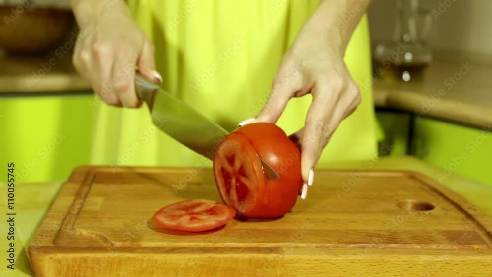 Woman slicing tomato. Female hands cut red tomato rings. Big knife. In ...