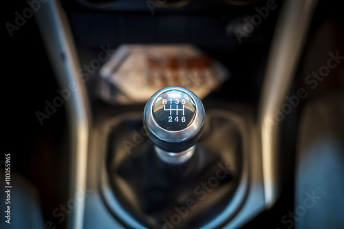 Close-up of a manual gear stick in a car interior, showing a six-speed transmission with reverse gear.