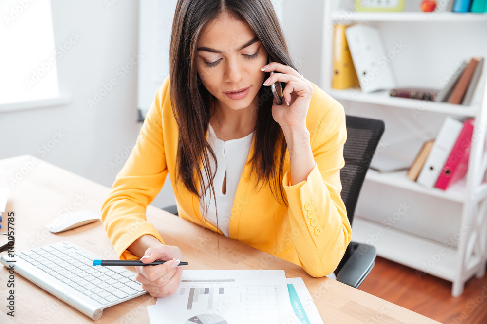 Businesswoman talking on the phone and analysing graphics