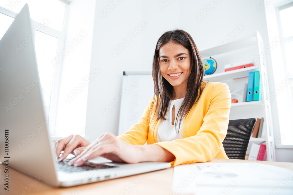 Happy businesswoman using laptop computer in office