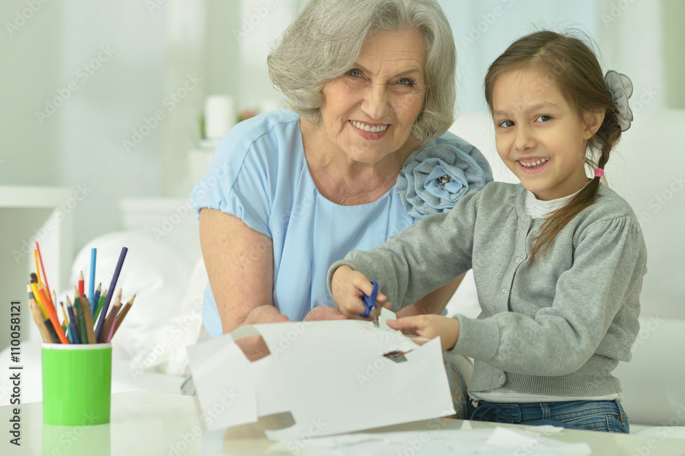 Obraz premium Grandmother with granddaughter cutting together