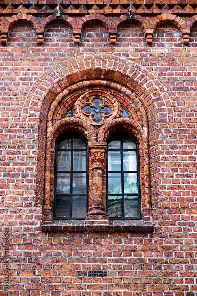 Fototapeta premium Window in an old red brick wall, with gothic elements as arch and rose windows